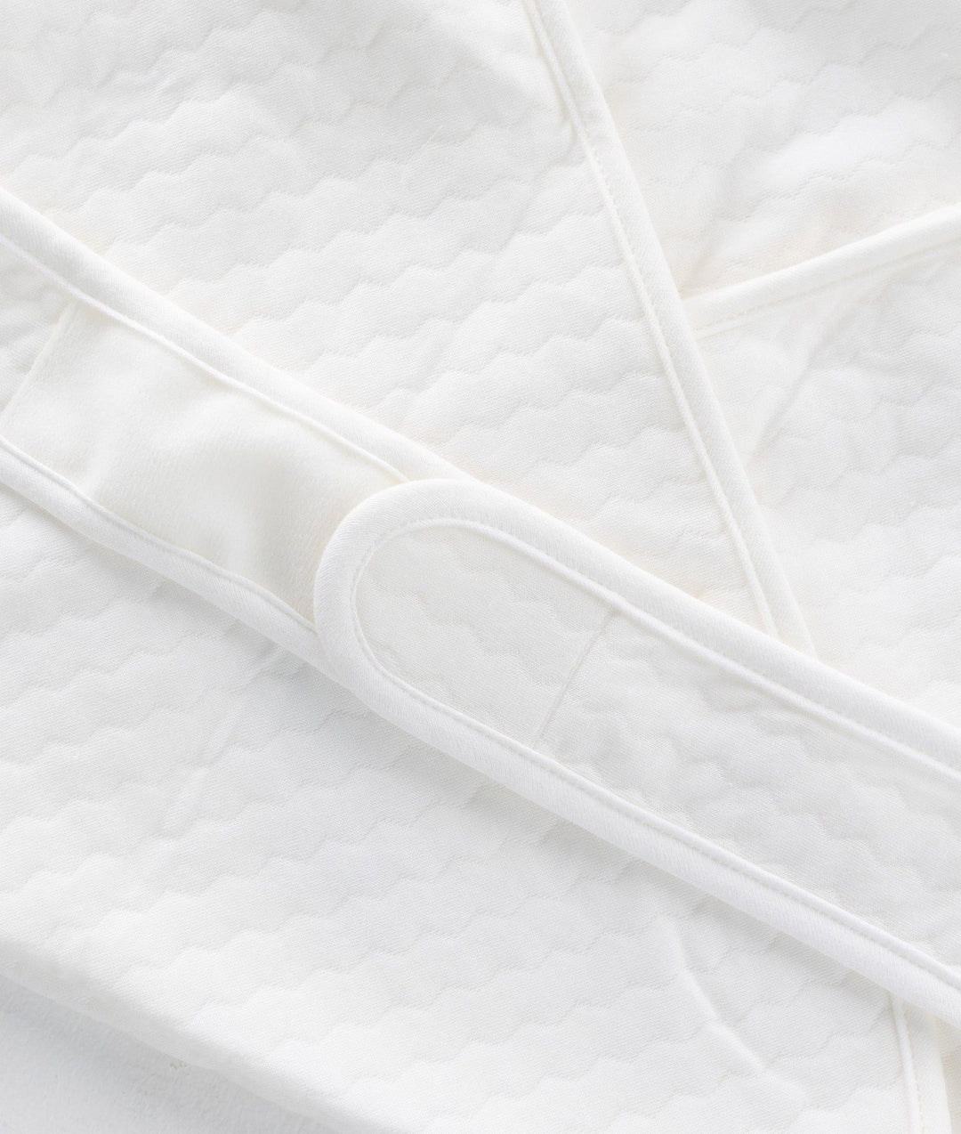 Macro detail of wavy quilted 100% cotton texture and loop fastener on swaddle