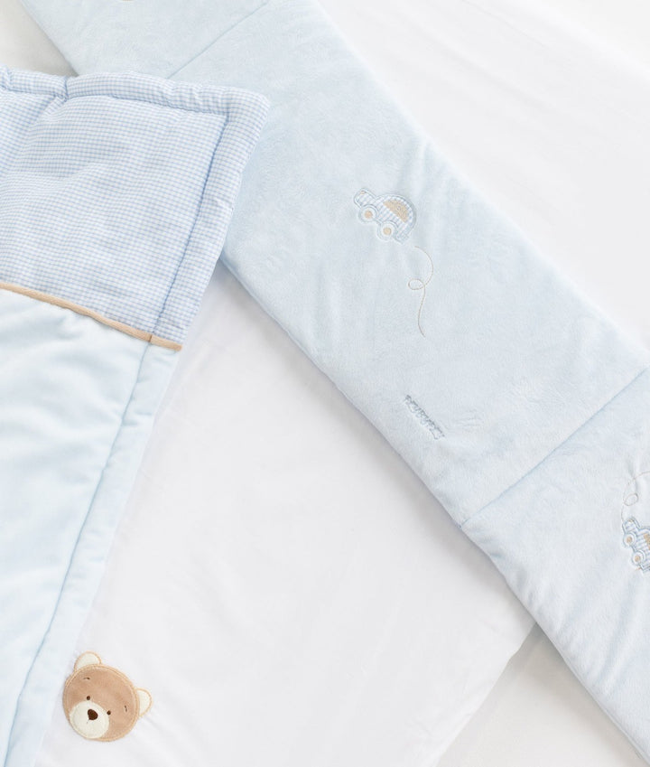 Bassinet set details: embroidered cars on bumper, tan trim, and bear patch on sheet