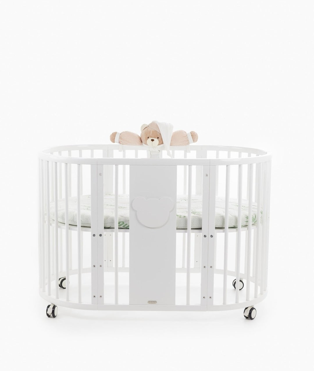 White baby cot with teddy bear design styled in a neutral nursery room