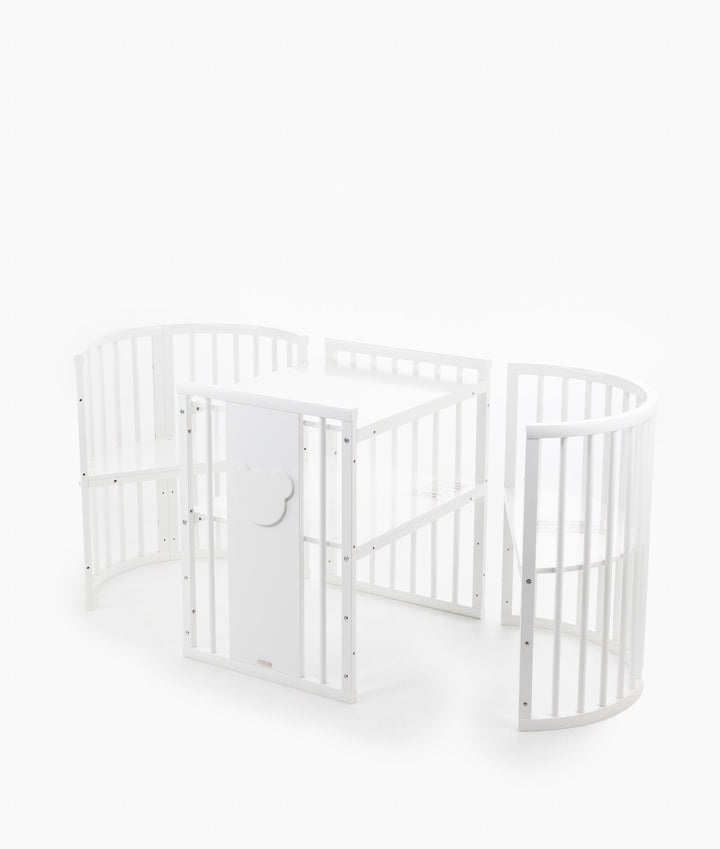 White baby cot with teddy bear design styled in a neutral nursery room