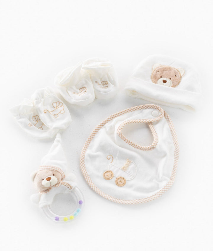 5-piece beige and white newborn gift set flat lay with rattle and booties