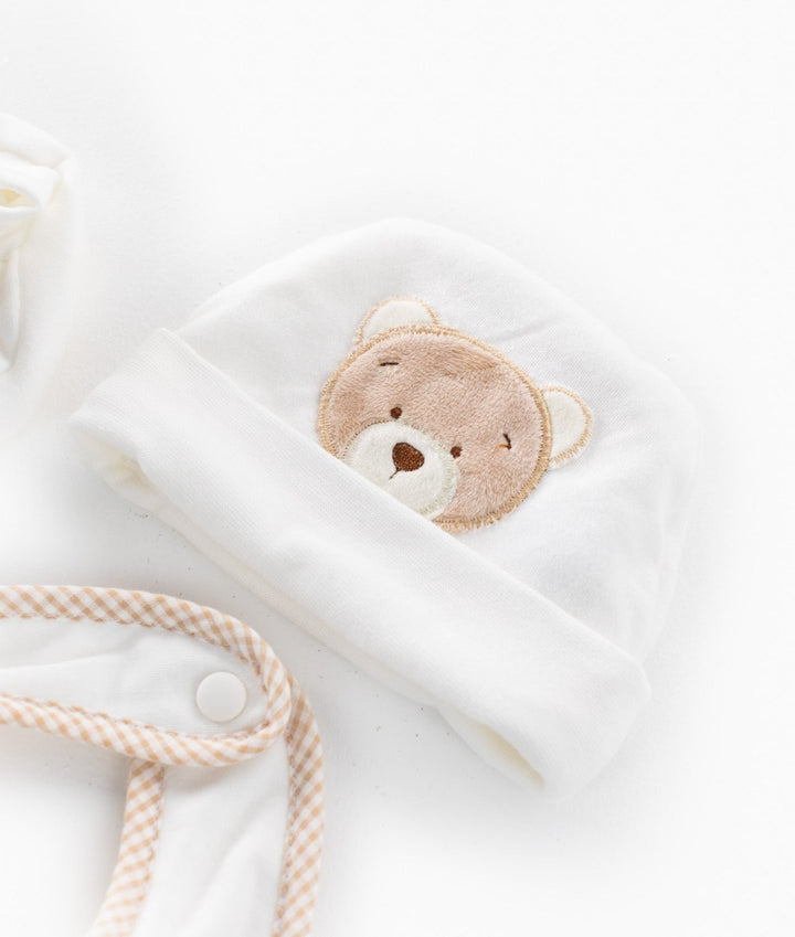 White knit baby hat with plush teddy bear face appliqué