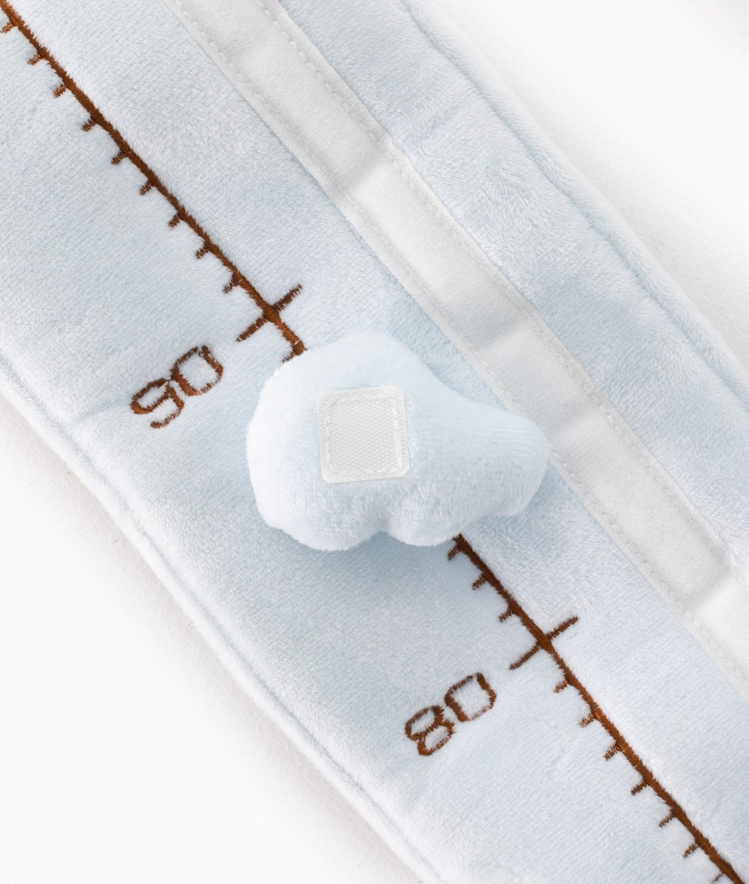 Close-up of soft light blue plush texture with brown embroidered measurement lines