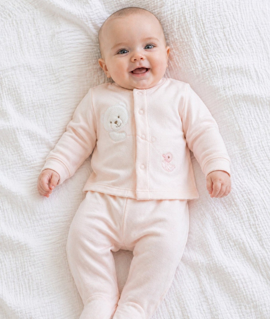 Baby wearing pink two-piece pyjama set with teddy bear and duck embellishments