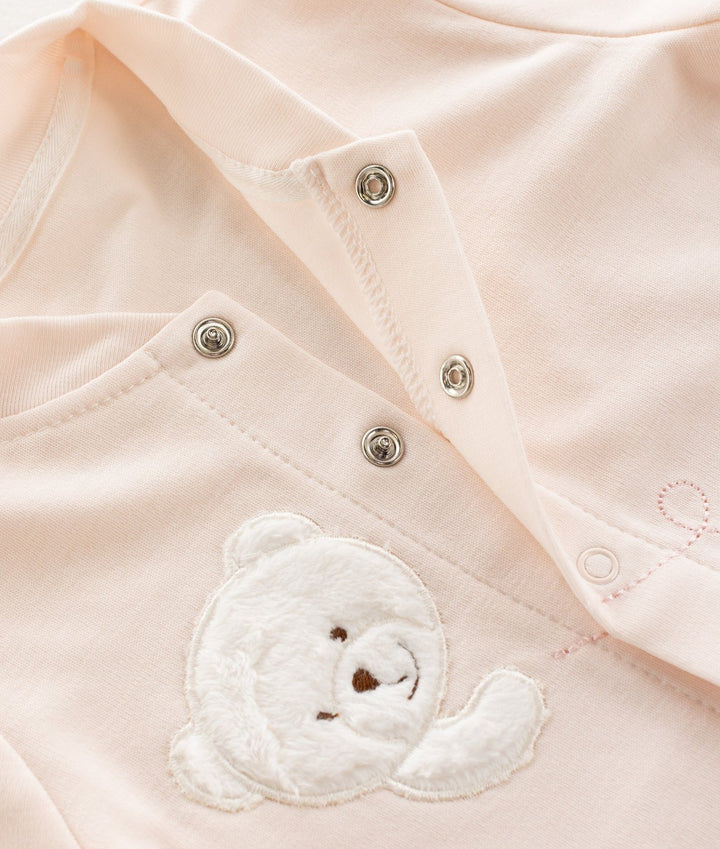 Pale pink pyjama fabric detail with silver snap buttons and plush teddy bear appliqué