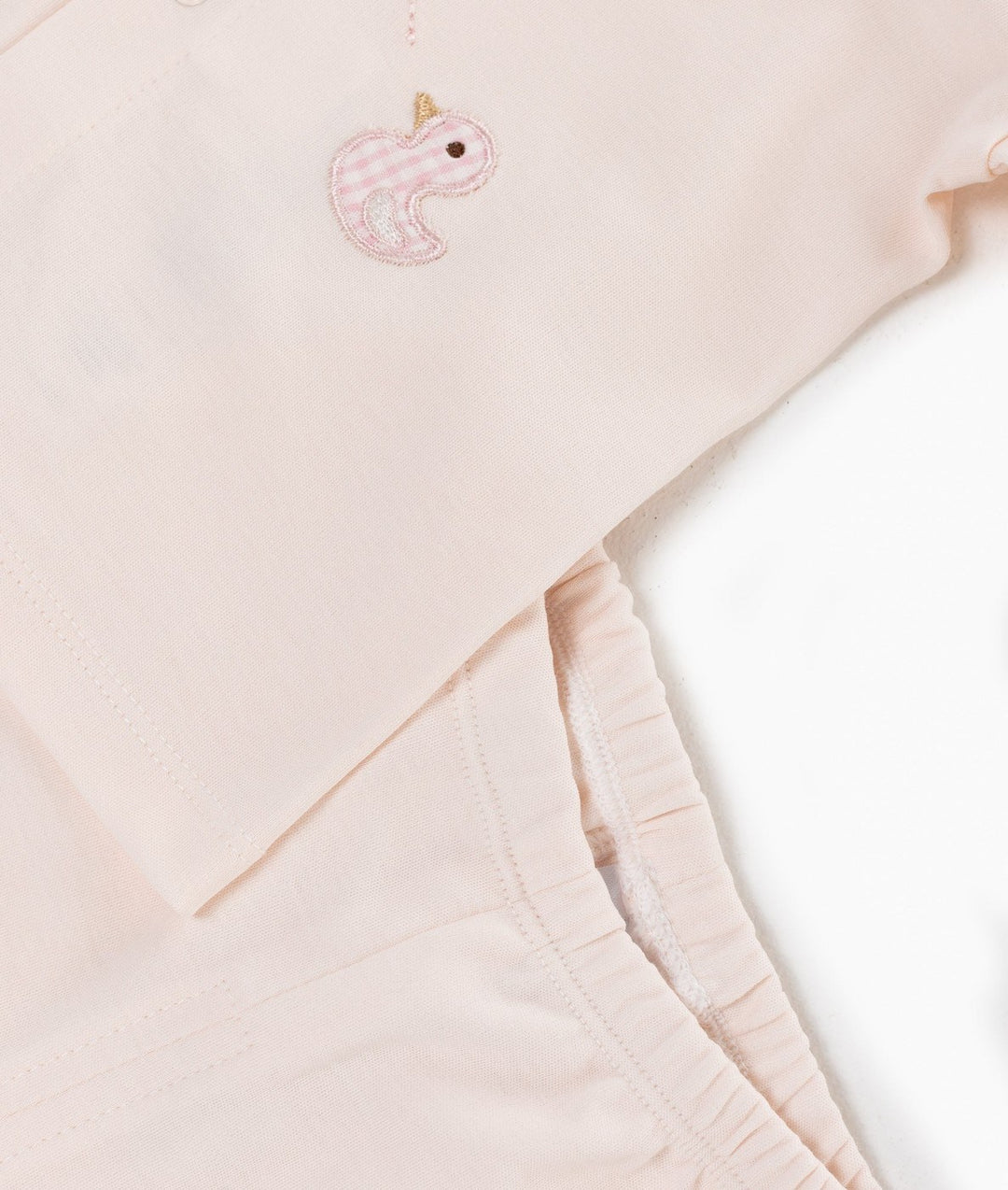 Close up of pink cotton fabric with gingham duck embroidery patch on waistband