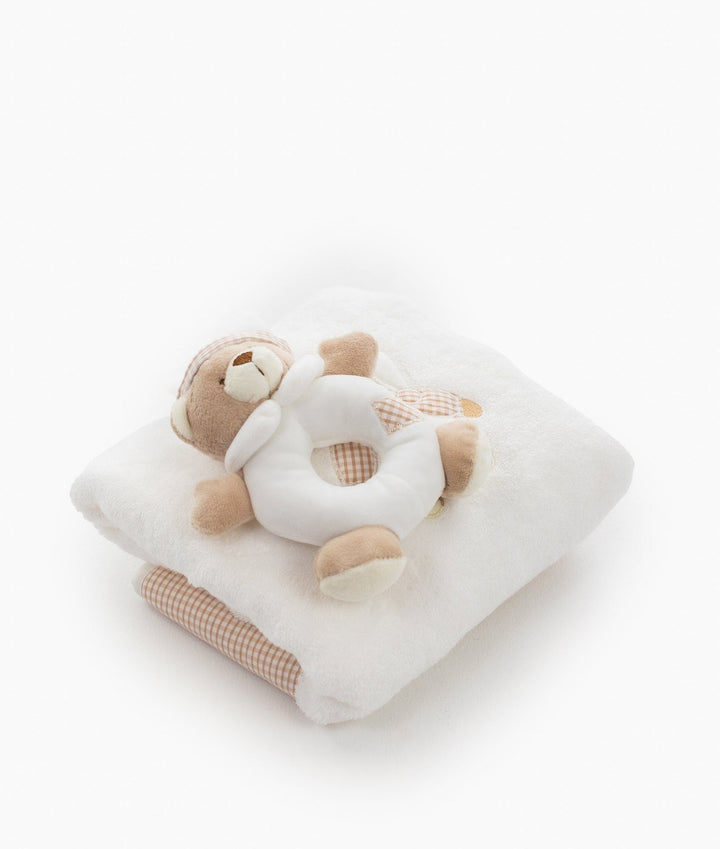 Beige plush bear rattle on folded white towel with gingham hem