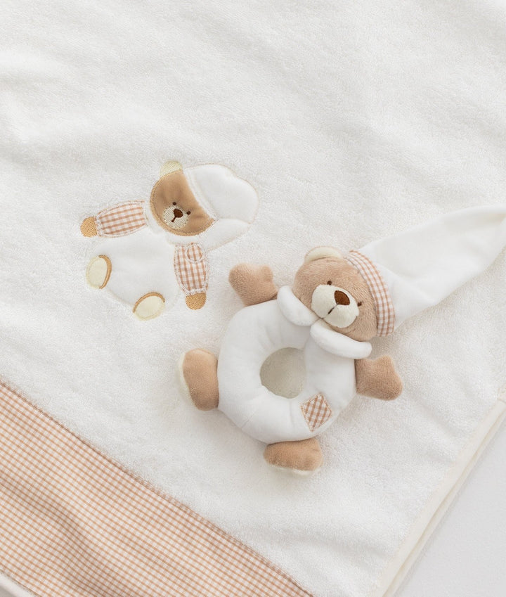 Macro view of white towel texture, embroidered bear, and beige gingham