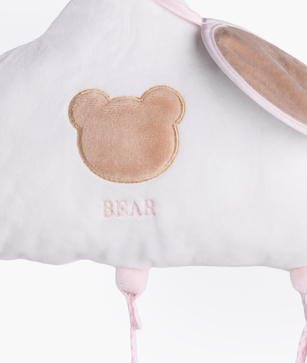 Detail shot of brown embroidered bear head outline on white plush fabric