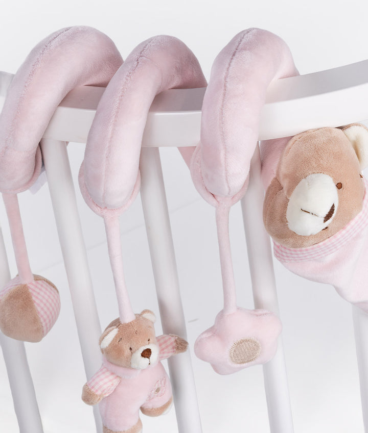 Light pink velour spiral activity toy wrapped over chair back with dangling sensory bear and star charms