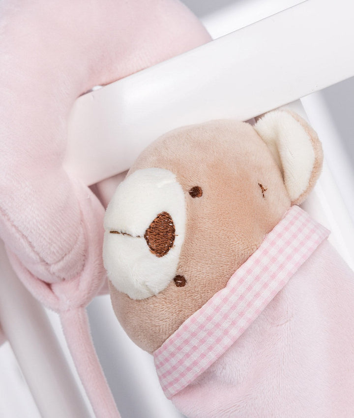 Macro detail of embroidered bear face and pink gingham trim on soft pink spiral activity toy