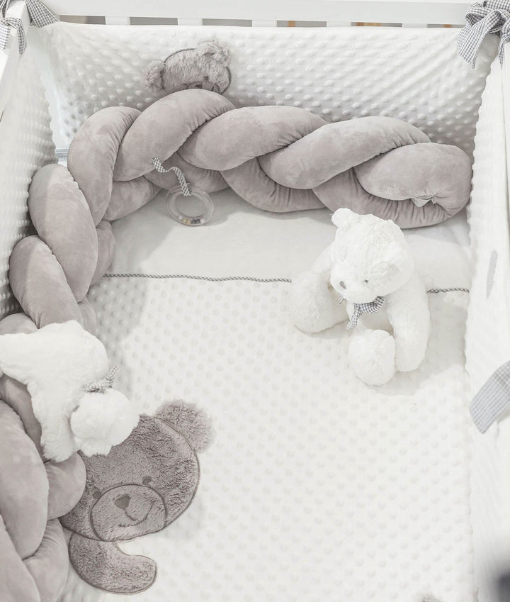 crib with grey braided bumper tied with bows and bear face applique sheet