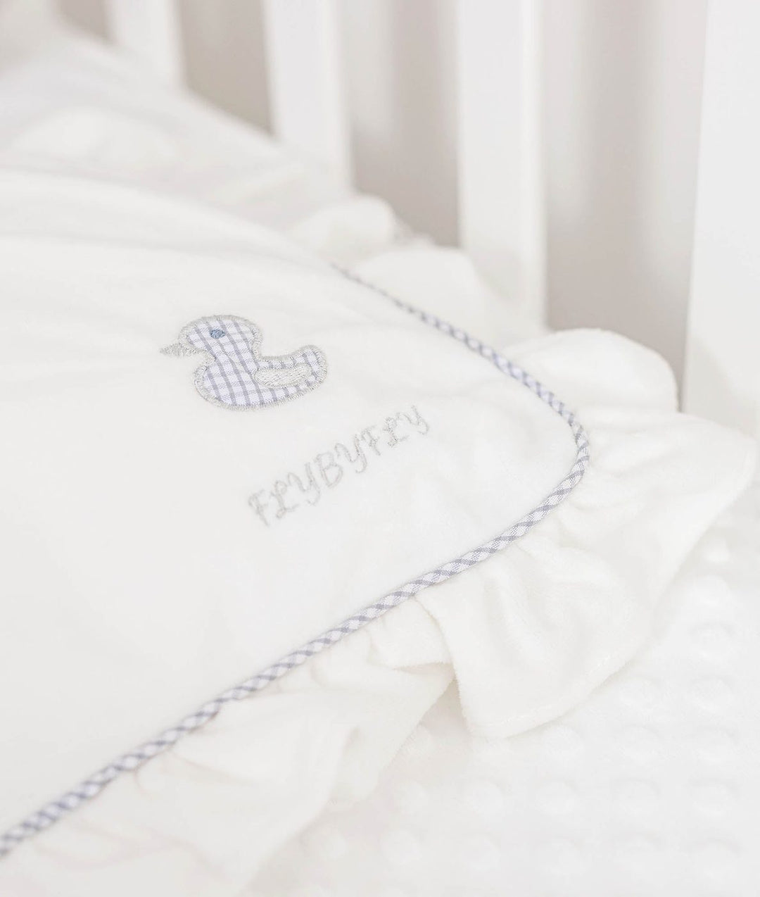 white pillow corner with blue gingham duck patch and FLYBYFLY embroidery