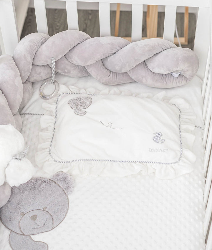 white ruffled pillow with grey braided trim and embroidered bear duck motifs