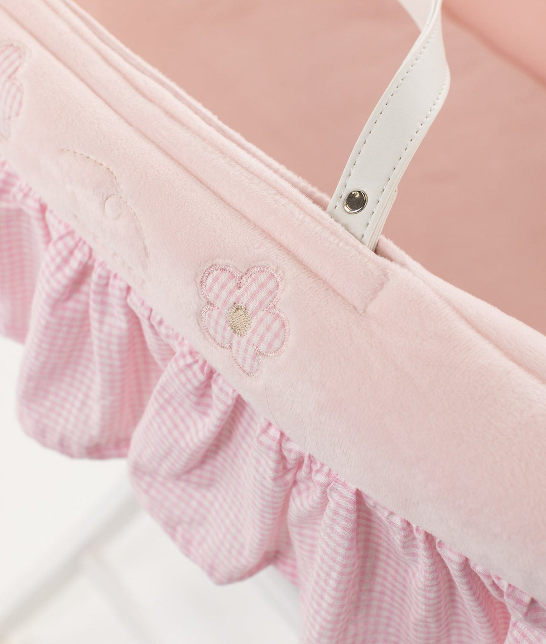 Macro shot of embroidered flower detail on pink velvet rim of Moses basket