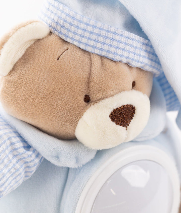 Detail of blue plush night light with embroidered nose, eyes, and white light housing