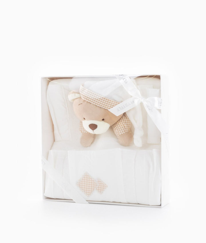 White gift box containing folded cream nursery organiser with beige gingham accents and teddy bear wearing checkered hat