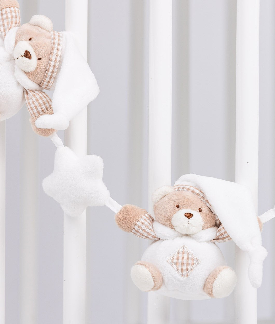 Soft white star connector between bears hanging on crib slats