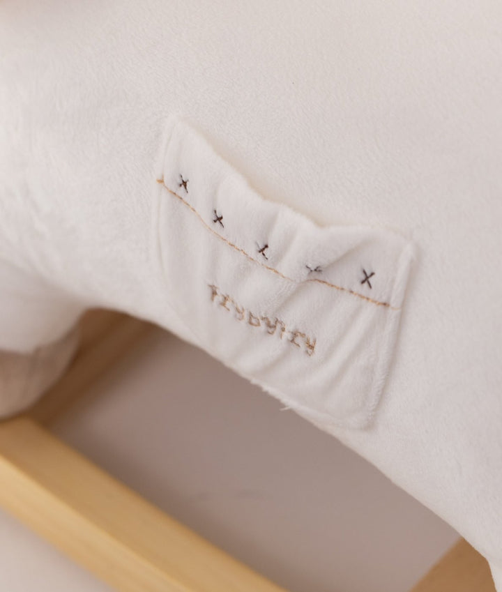Embroidered brand patch detail on beige rocking animal plush toy