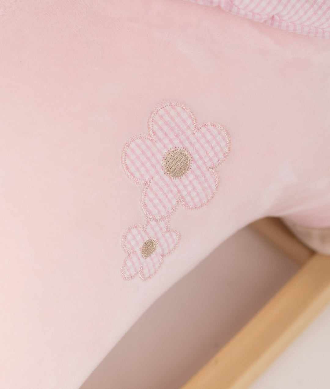 Close-up of embroidered flower detail on pink gingham fabric