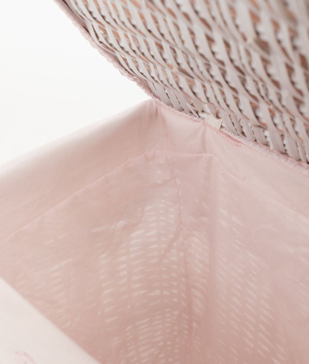 Close-up of smooth light pink fabric lining with elastic binding in wicker basket