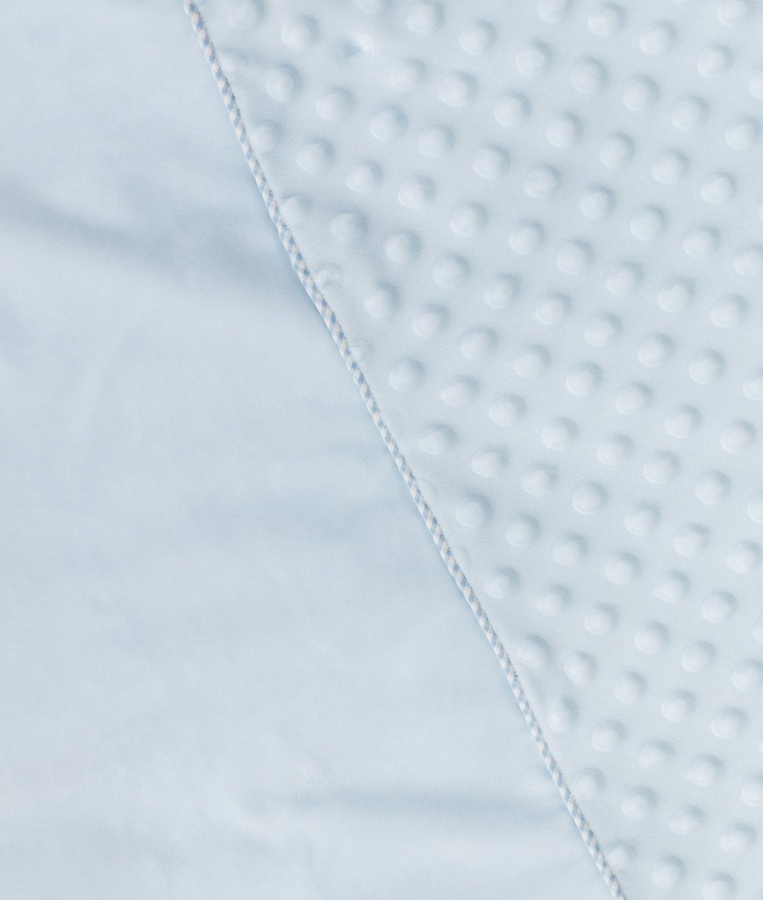Corner detail of light blue bubble quilt seam joining textured dots to smooth white edge