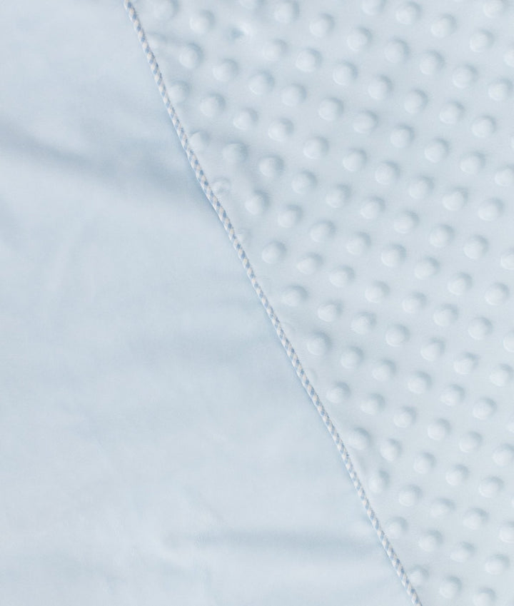 Corner detail of light blue bubble quilt seam joining textured dots to smooth white edge