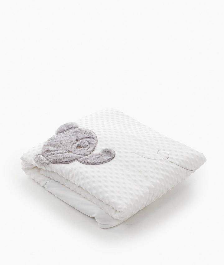 Folded white toddler bubble quilt with grey teddy bear appliqué