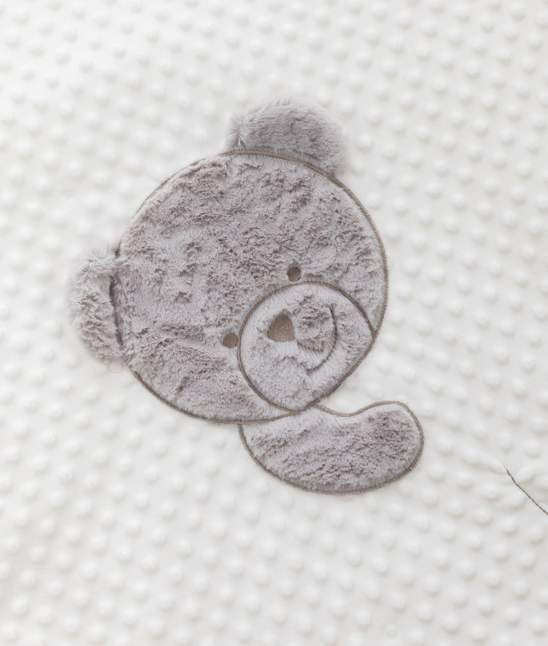 Plush grey teddy bear face patch on dimpled white bubble fabric