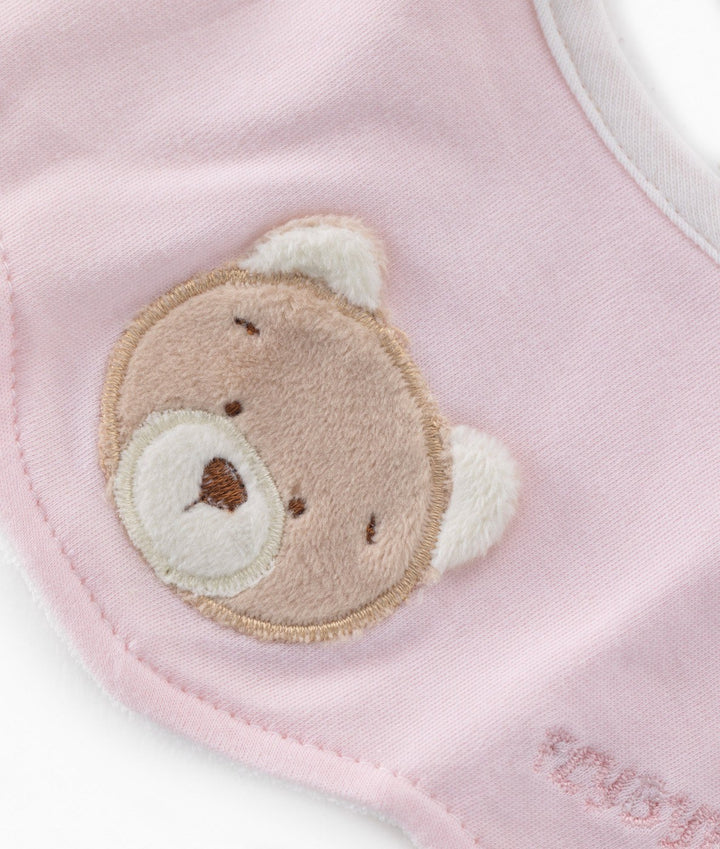 Close-up of pink baby bib teddy bear patch with embroidered face and scalloped edge