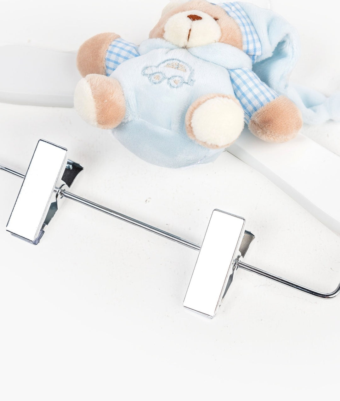 Close-up of silver metal clips on wooden baby hanger with blue teddy bear detail